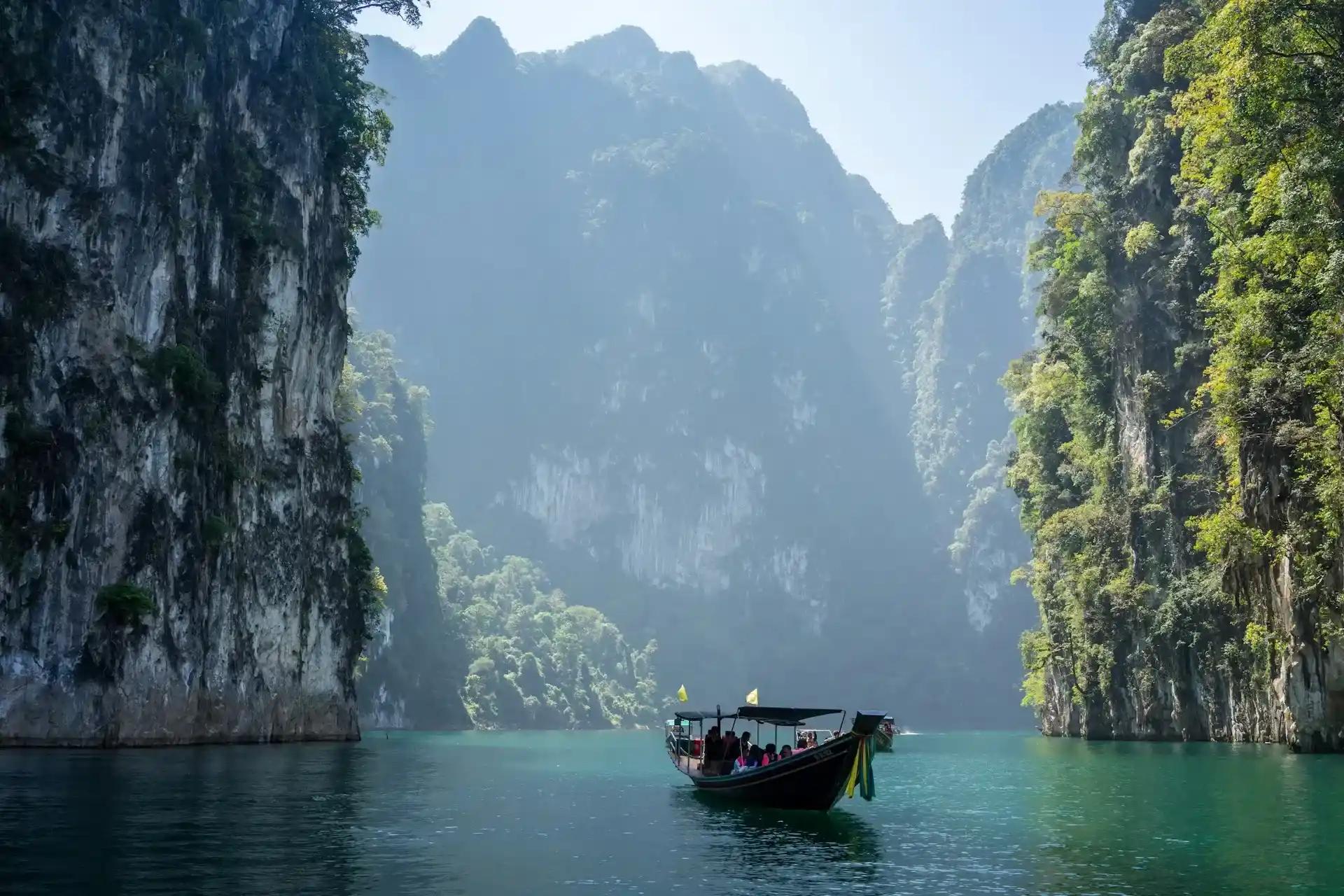 Barca tra montagne rocciose con vegetazione, a Khao Sok National Park, Thailandia