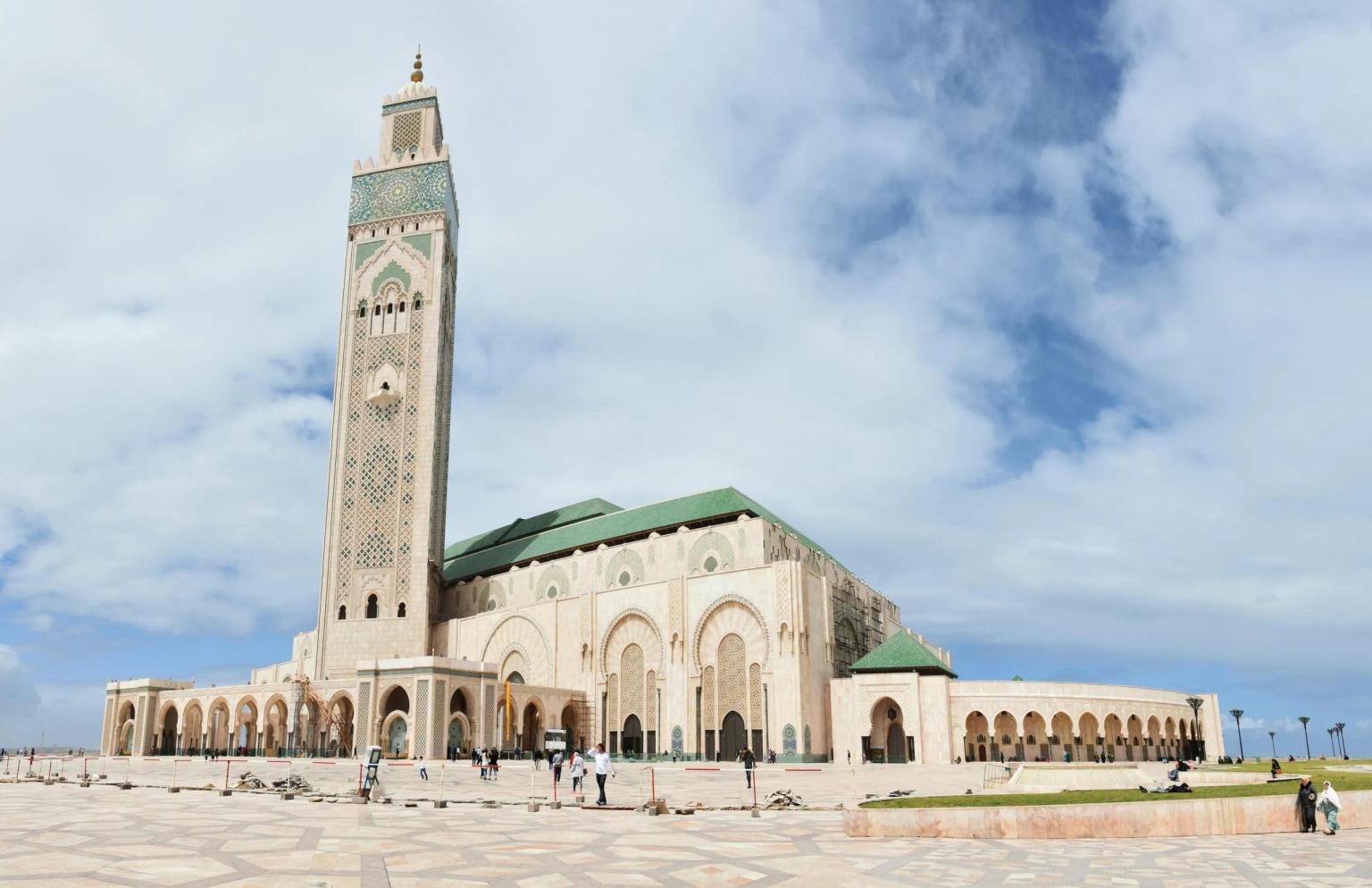 Gran mezquita con torre alta y arquitectura islámica en un día nublado.