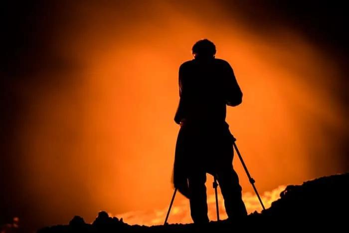 Silueta de un fotógrafo frente a un paisaje ardiente y luminoso.
