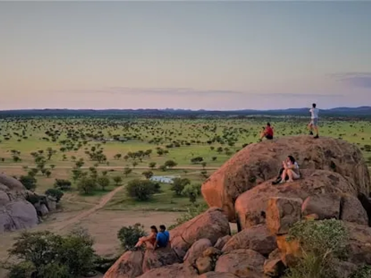 pessoas sentadas numa rocha com vista para arvores verdes na namibia