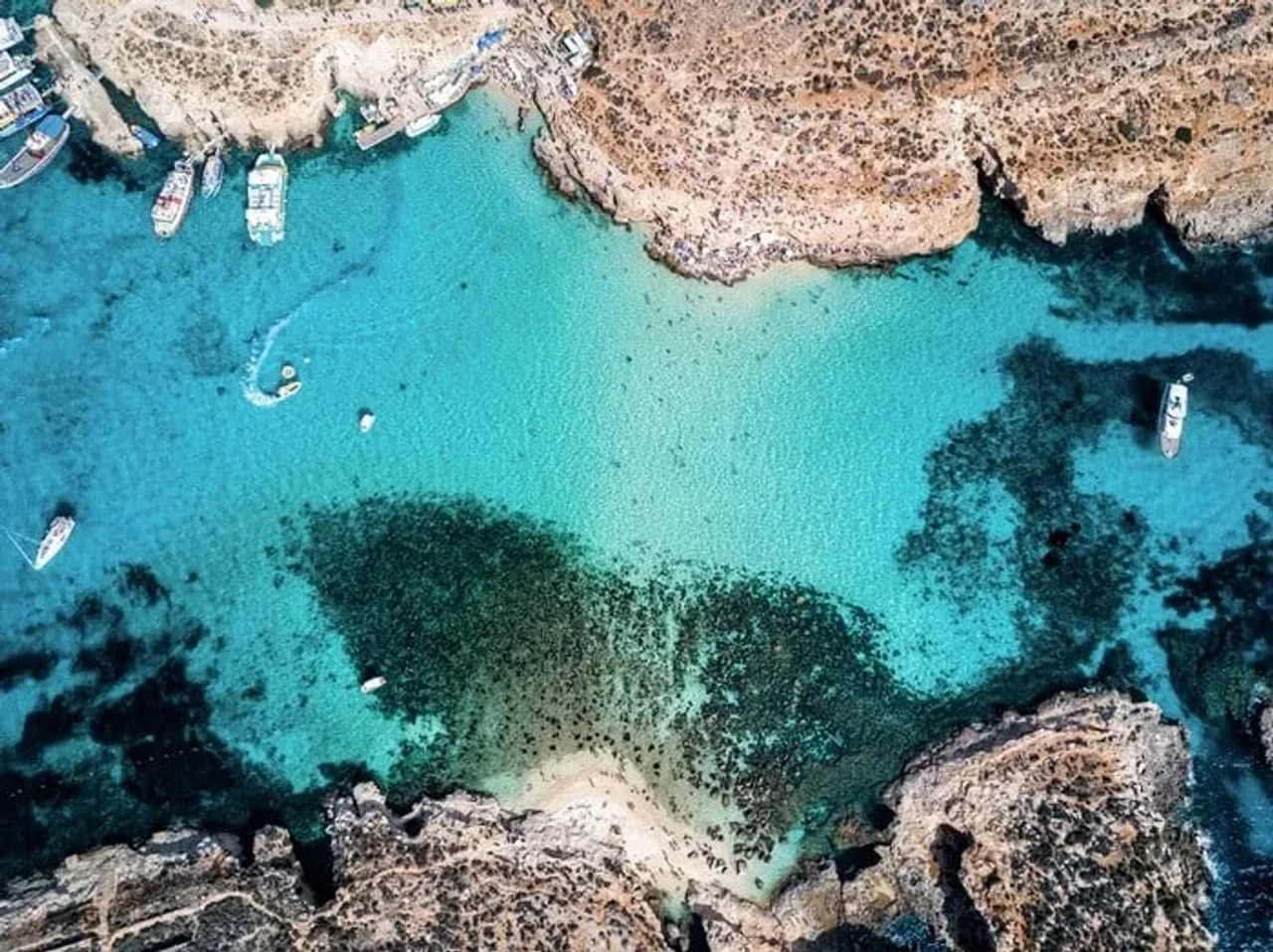 Vista aérea de águas cristalinas e barcos em uma baía de Malta.