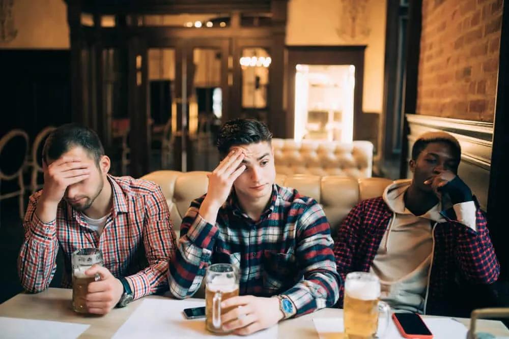 tres amigos chateados num bar com cervejas