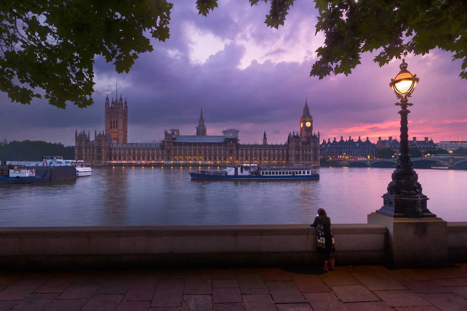 Vista do Parlamento Britânico ao entardecer, com barco no rio Tâmisa.