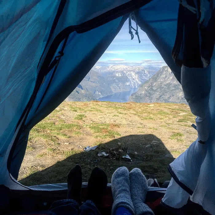 Vista desde una tienda de campaña hacia un paisaje montañoso y un fiordo.