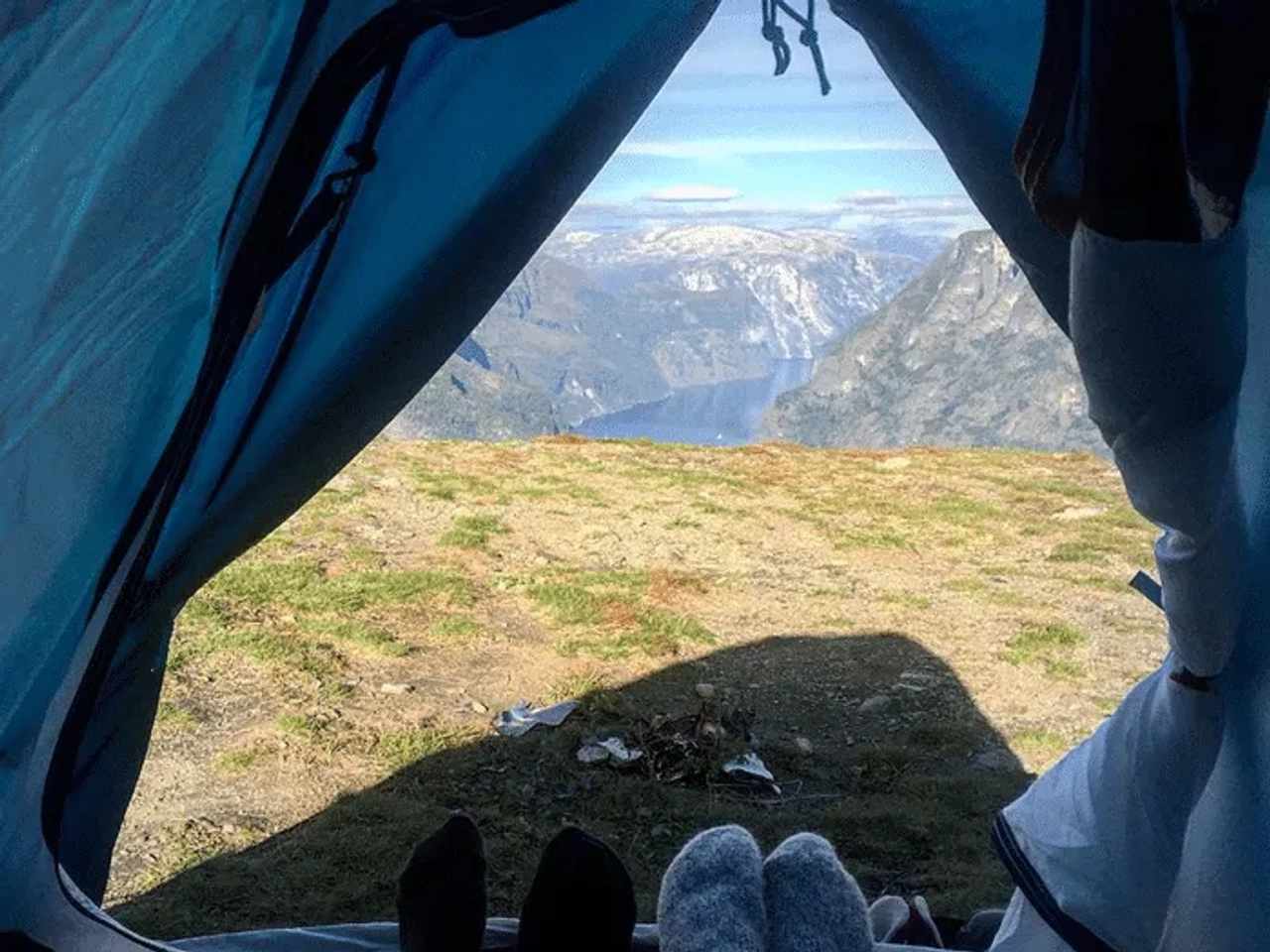 Vista desde una tienda de campaña hacia un paisaje montañoso y un fiordo.