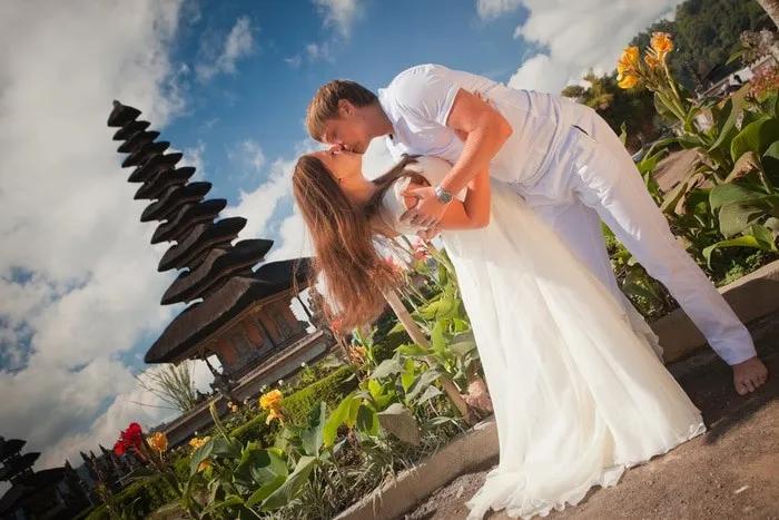 Pareja de novios en un paisaje tropical con templo balinés de fondo.