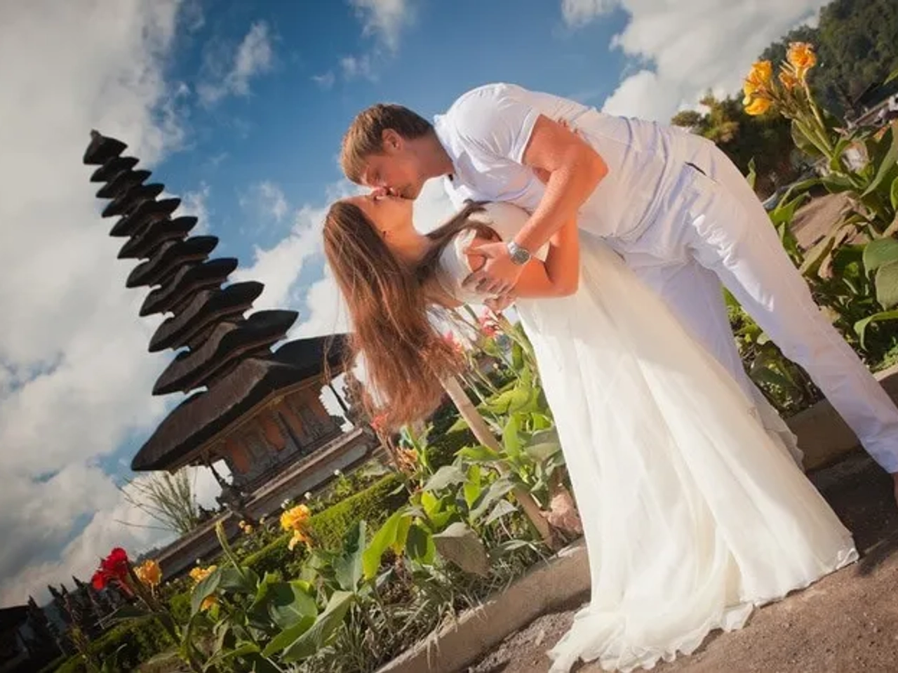 Pareja de novios en un paisaje tropical con templo balinés de fondo.