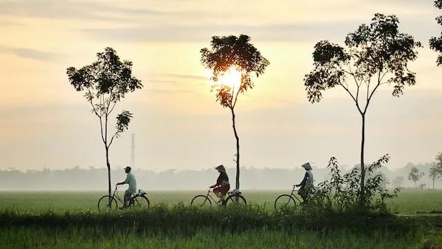 3 people riding a bike wearing typical cultural hats in indonesia