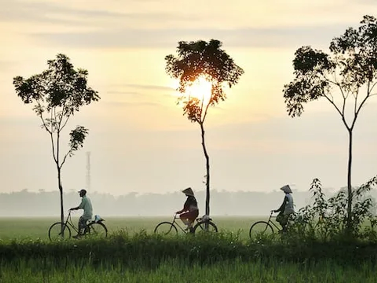 3 people riding a bike wearing typical cultural hats in indonesia