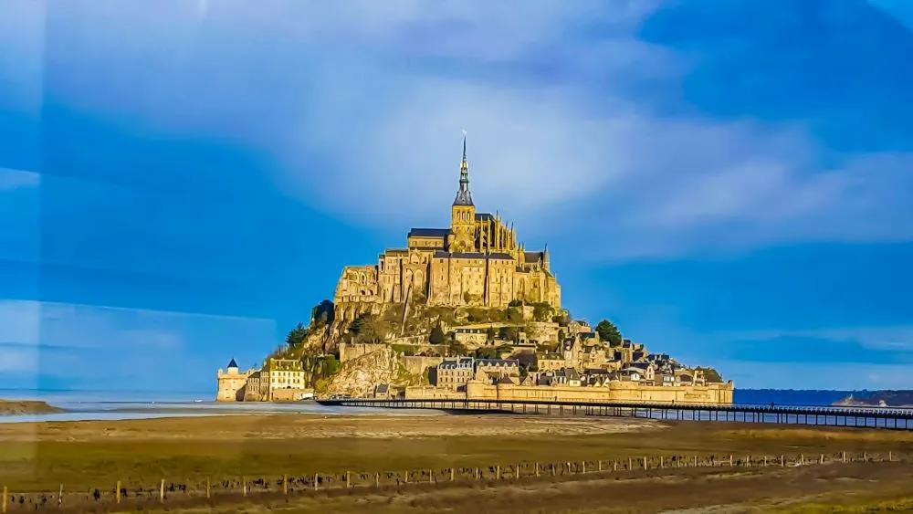 Mont Saint-Michel, una isla con una abadía, rodeada de mar y tierra.