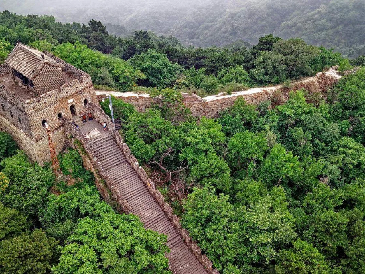 Muralha da China cercada por vegetação, destacando sua estrutura histórica e paisagem natural.