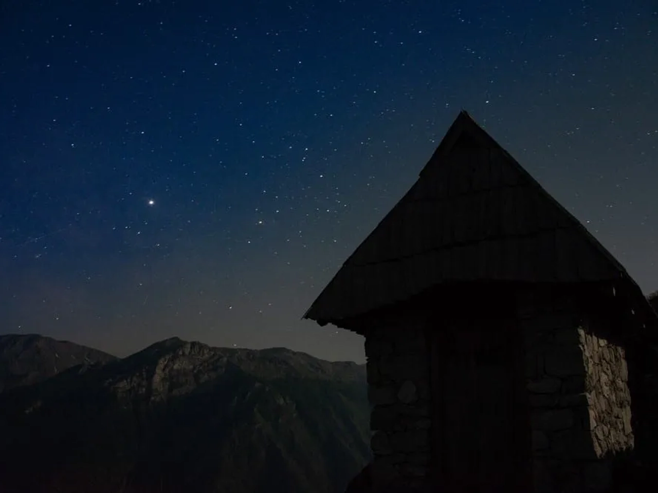 Casa de piedra bajo un cielo estrellado en las montañas de Bosnia.