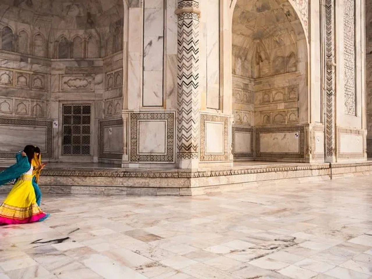 Mujer con vestido colorido camina por el interior del Taj Mahal.