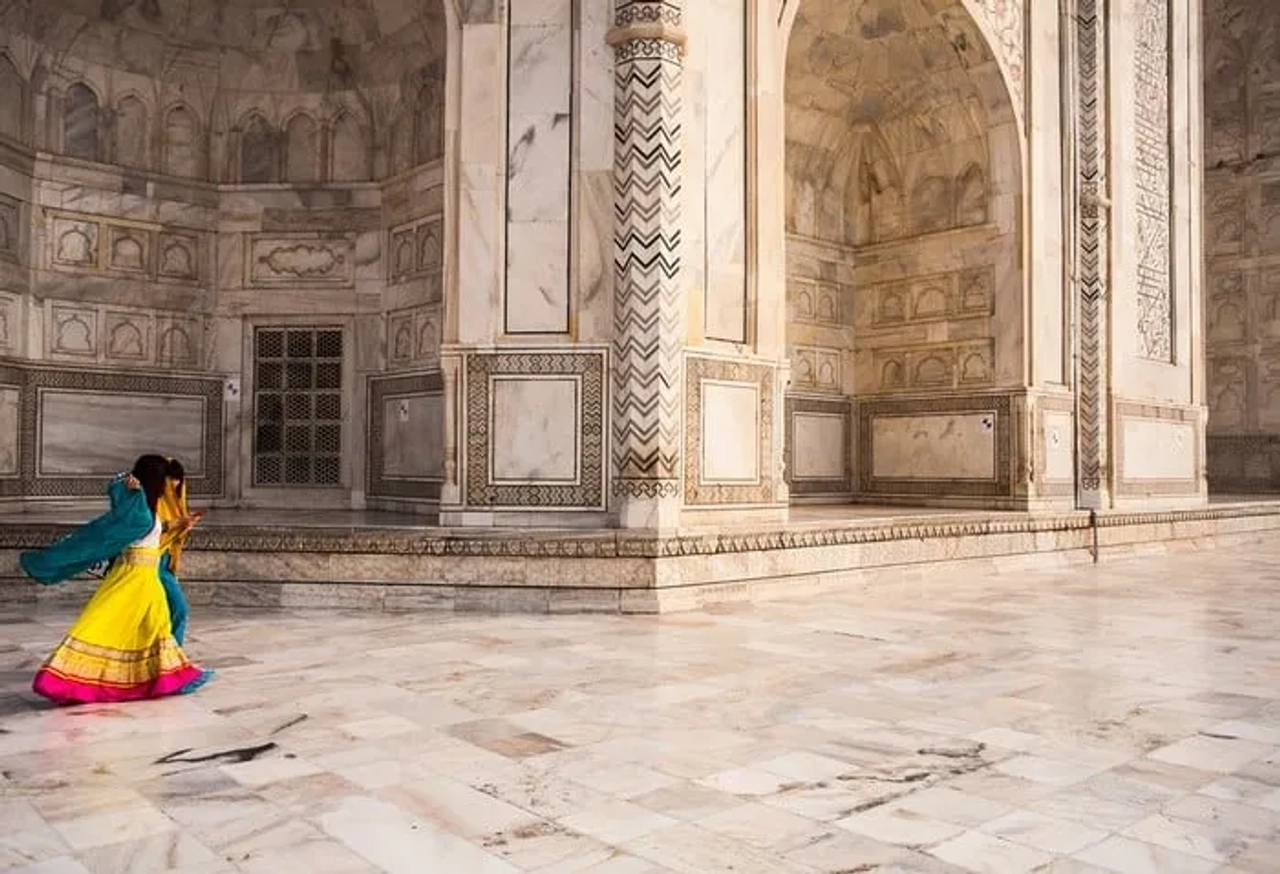 Mujer con vestido colorido camina por el interior del Taj Mahal.