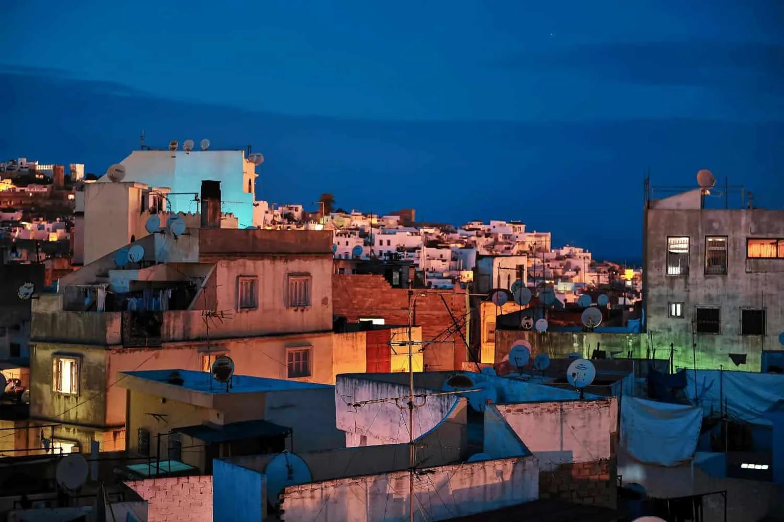 Vista noturna das casas de Tânger, com antenas e iluminação colorida.
