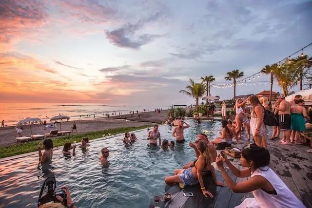 pessoas na piscina infinita no bar de praia the lawn em Canggu na indonesia