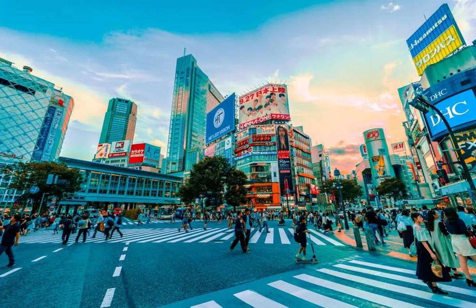 Cruce peatonal en Shibuya, Tokio, con edificios y publicidad iluminada.