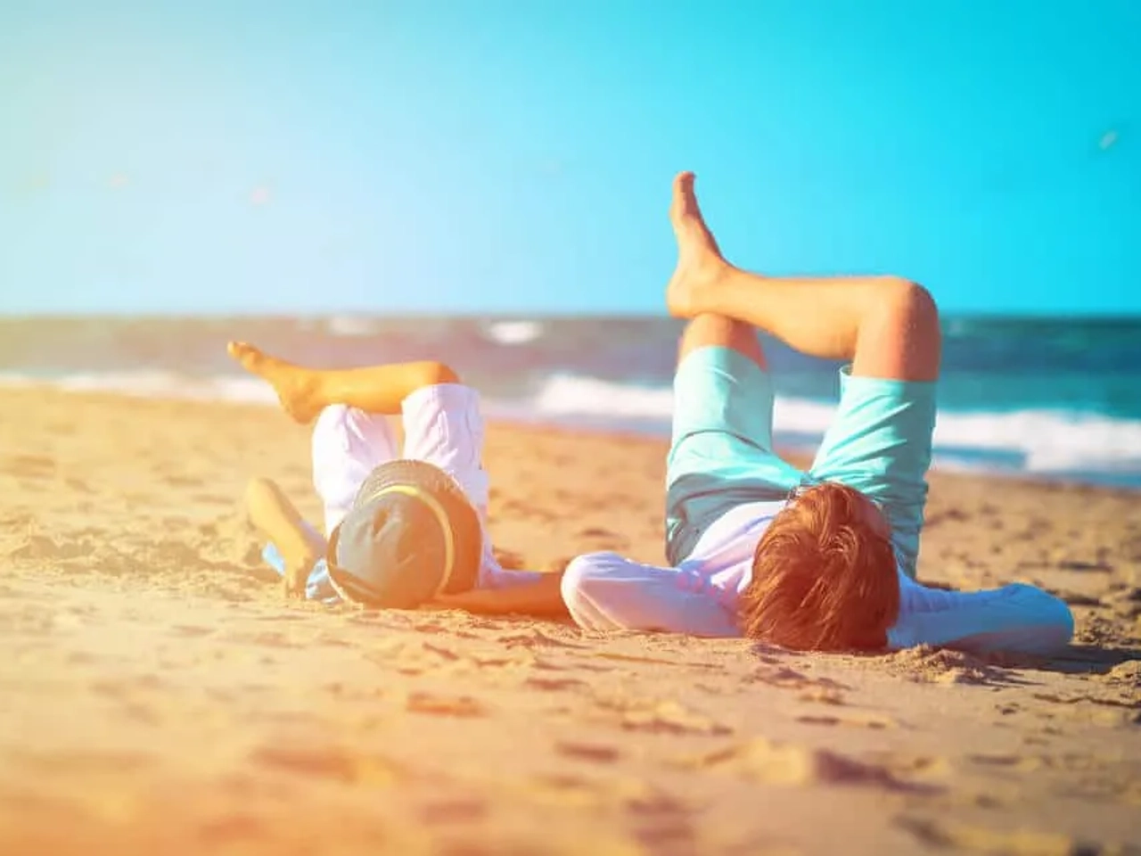 duas crianças deitadas na areia