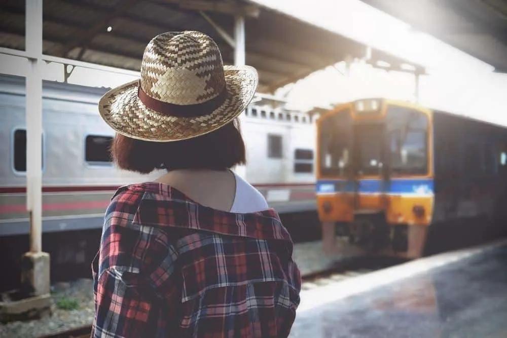 senhora com chapéu à espera do comboio