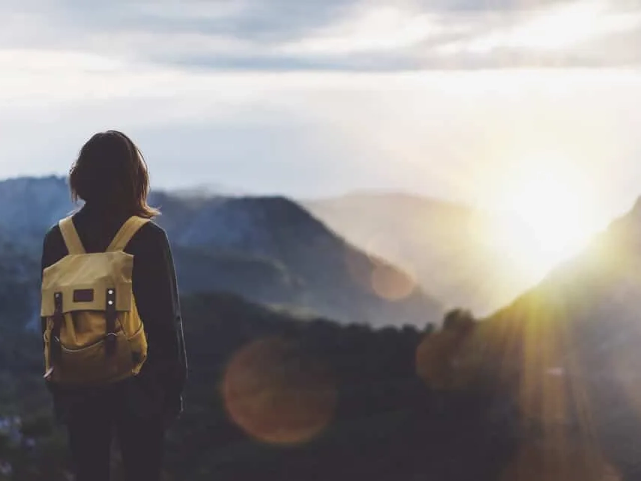 rapariga com mochila as costas olha para o horizonte