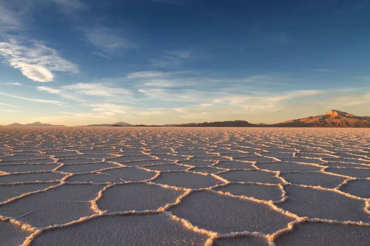 Salar de Uyuni, vasto desierto de sal con montañas al fondo y cielo despejado.