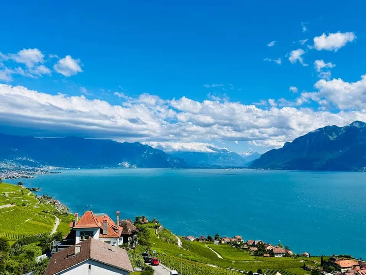 Vista panorâmica do Lago de Genebra, cercado por montanhas e vinhedos.