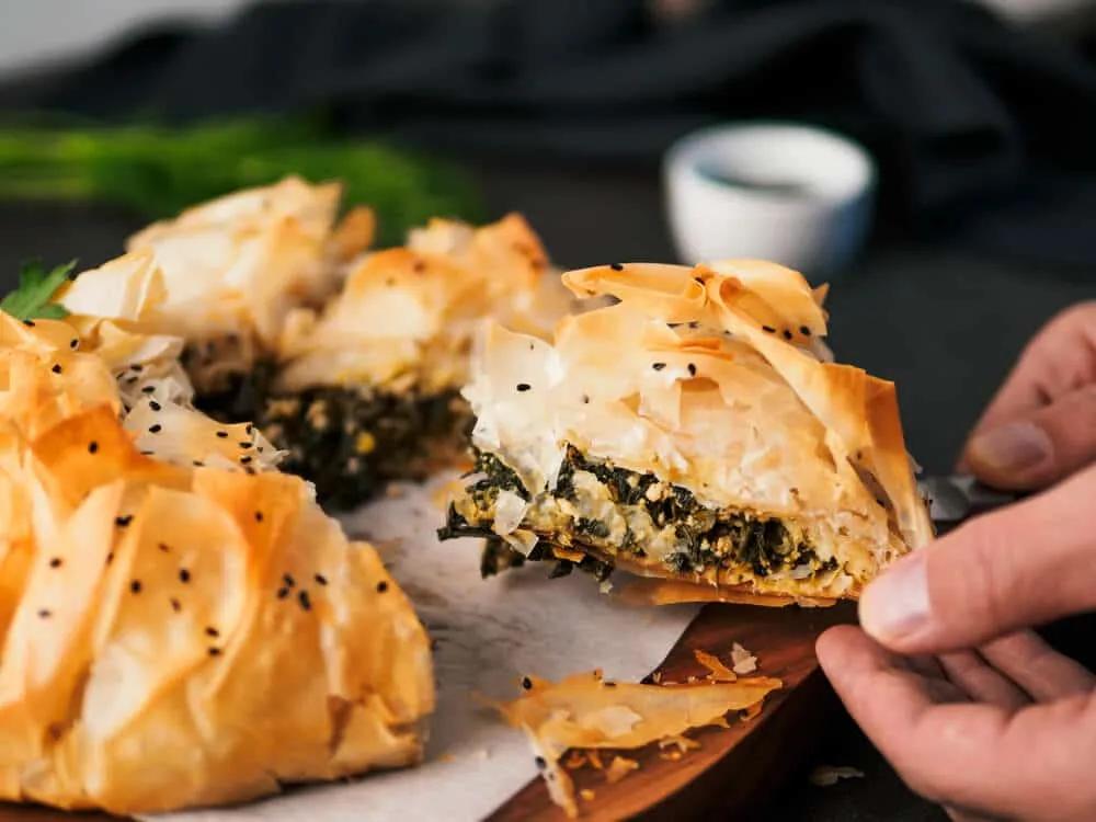 maos a pegar num pedaço de tarte spanakopita