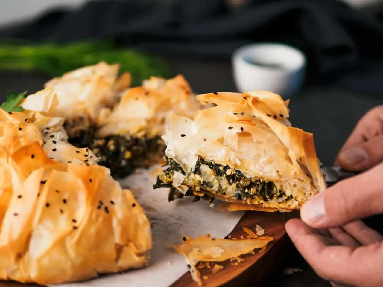 maos a pegar num pedaço de tarte spanakopita