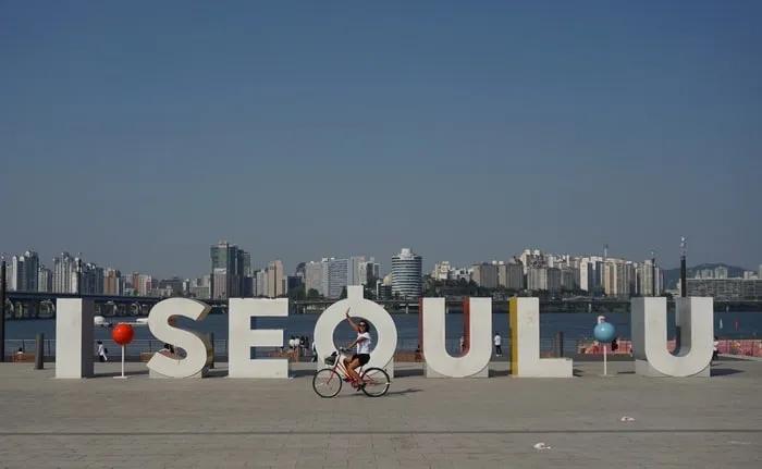 Letra gigante "I SEOUL U" con ciclista y skyline de Seúl al fondo.