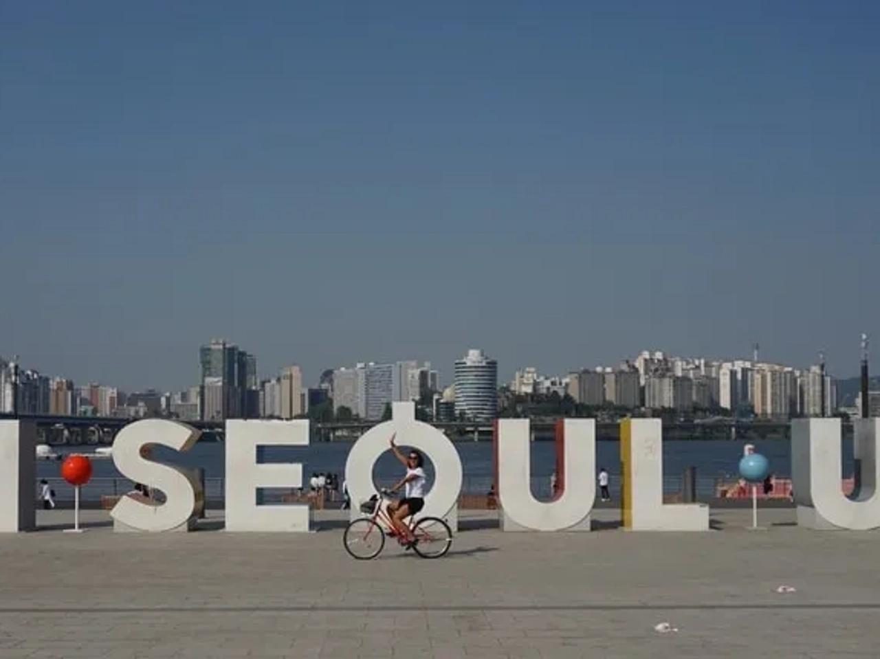 Letra gigante "I SEOUL U" con ciclista y skyline de Seúl al fondo.