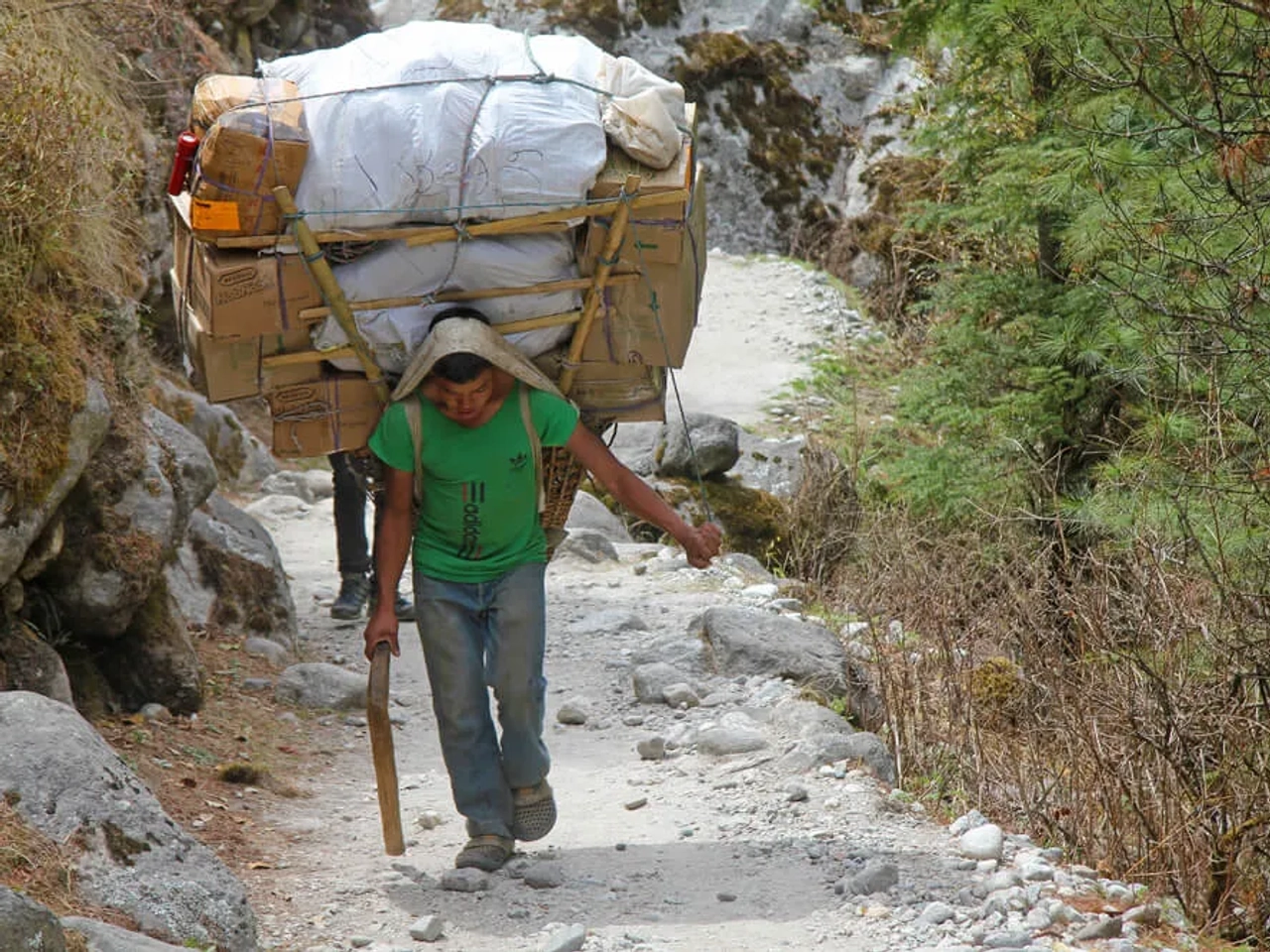 um sherpa a carregar varios fardos pela montanha acima