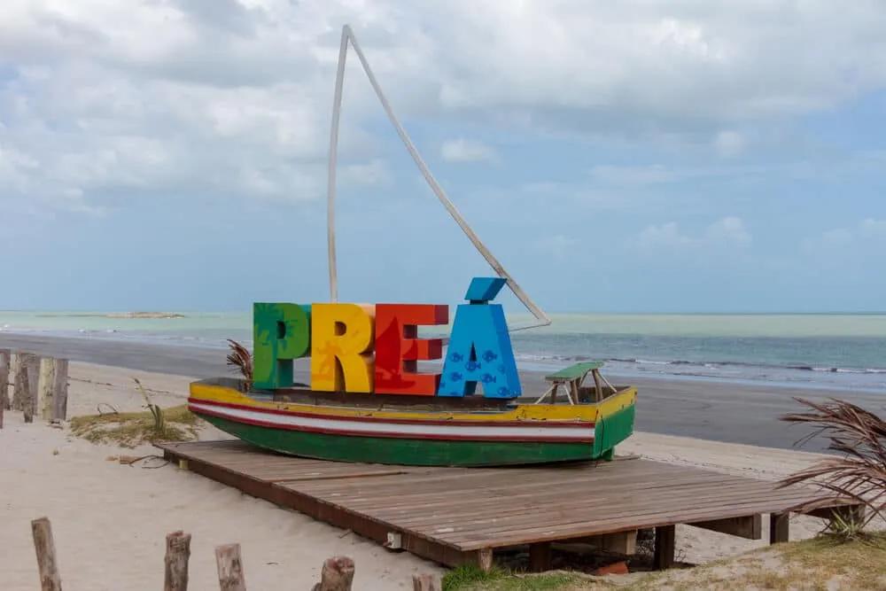 barco atracado com letras que formam a palavra Preá e mar no fundo