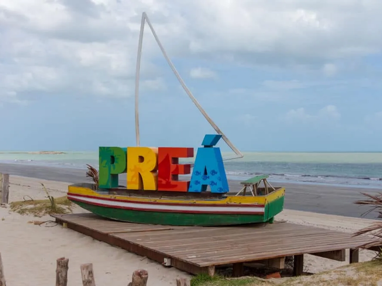 barco atracado com letras que formam a palavra Preá e mar no fundo