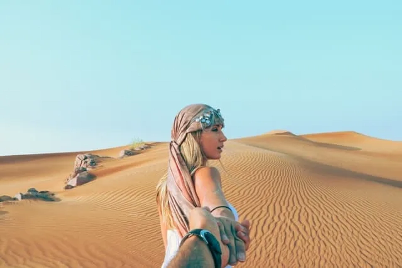 duas pessoas a dar as mãos no deserto no dubai