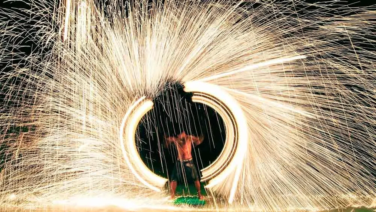 Spettacolo con fuoco durante il Full Moon Party a Koh Phangan, con scie luminose circolari sulla spiaggia di notte.