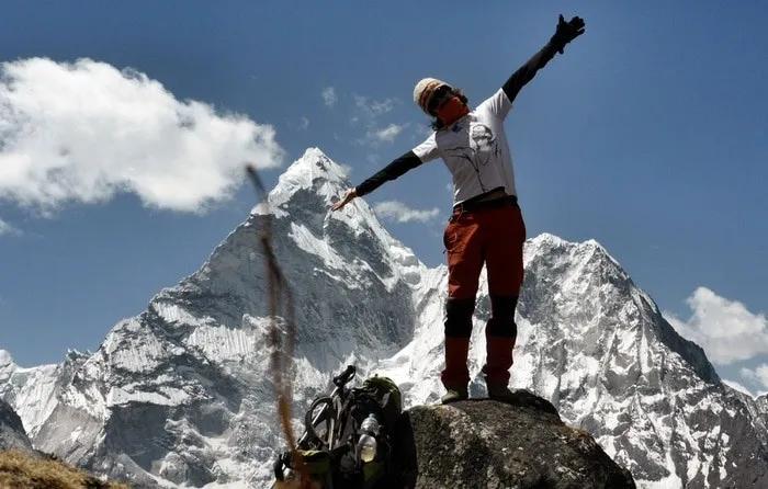 Persona en la cima de una montaña, disfrutando del paisaje nevado. Mochila a su lado.