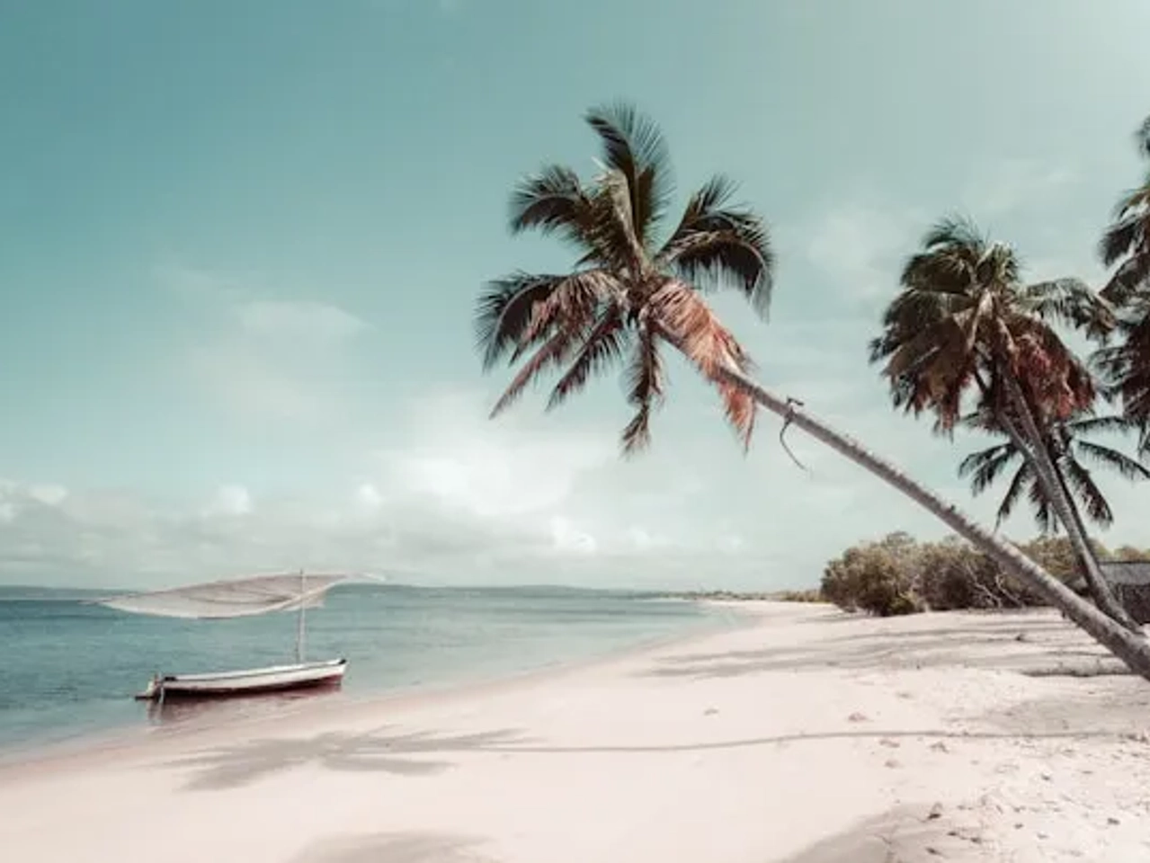 barco atracado ma agua azul turquesa duma praia em moçambique