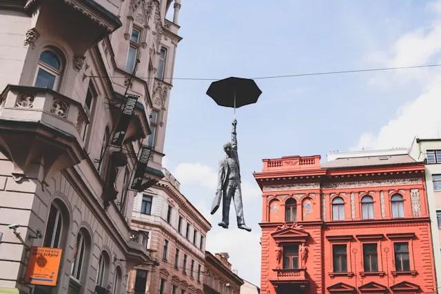 estatua de um homem a segurar um guarda chuva em praga