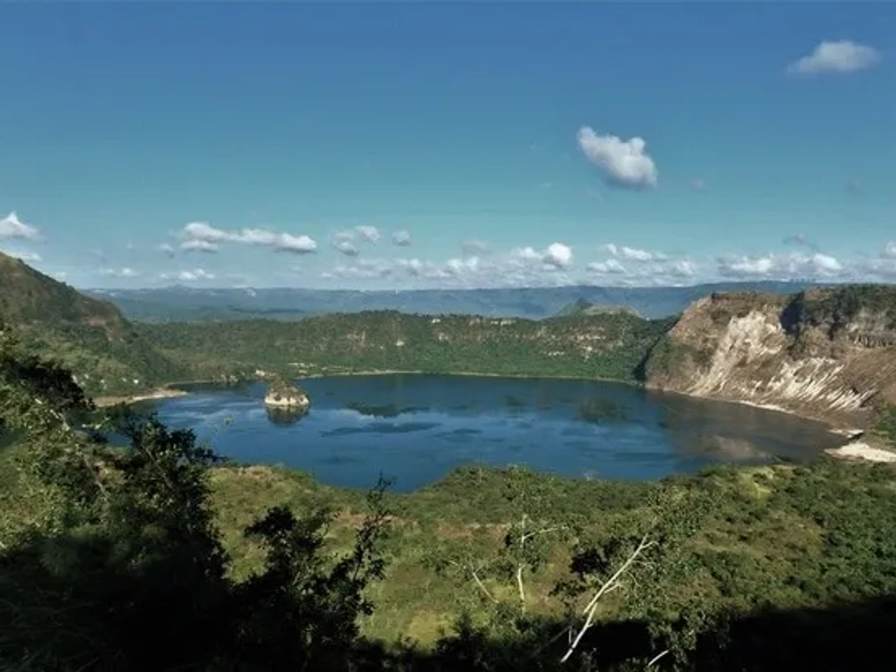 Vista panorámica de un lago rodeado de montañas y vegetación.