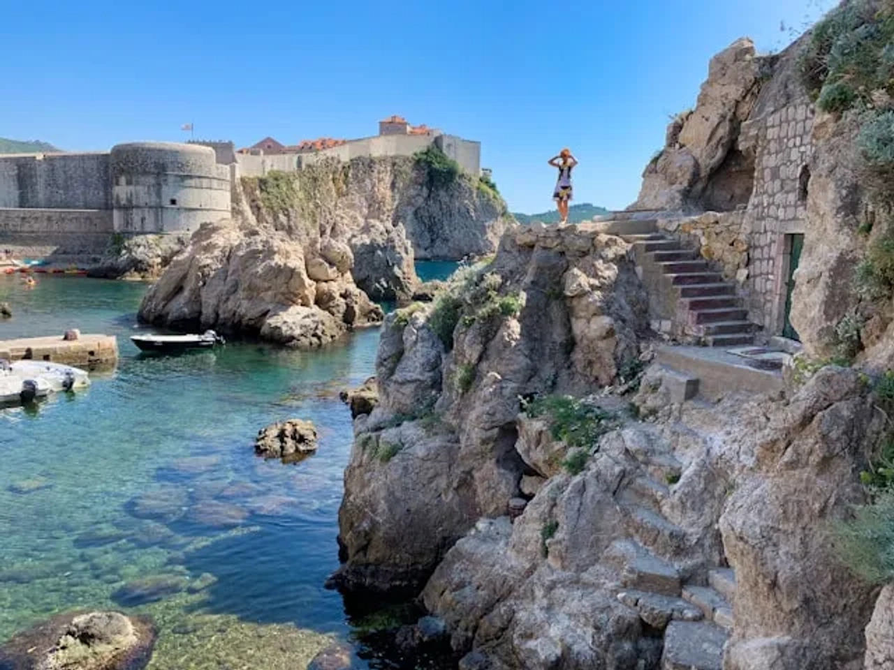 mulher em rocha ao pé do mar azul turquesa em Dubrovnik-Neretva, Croacia