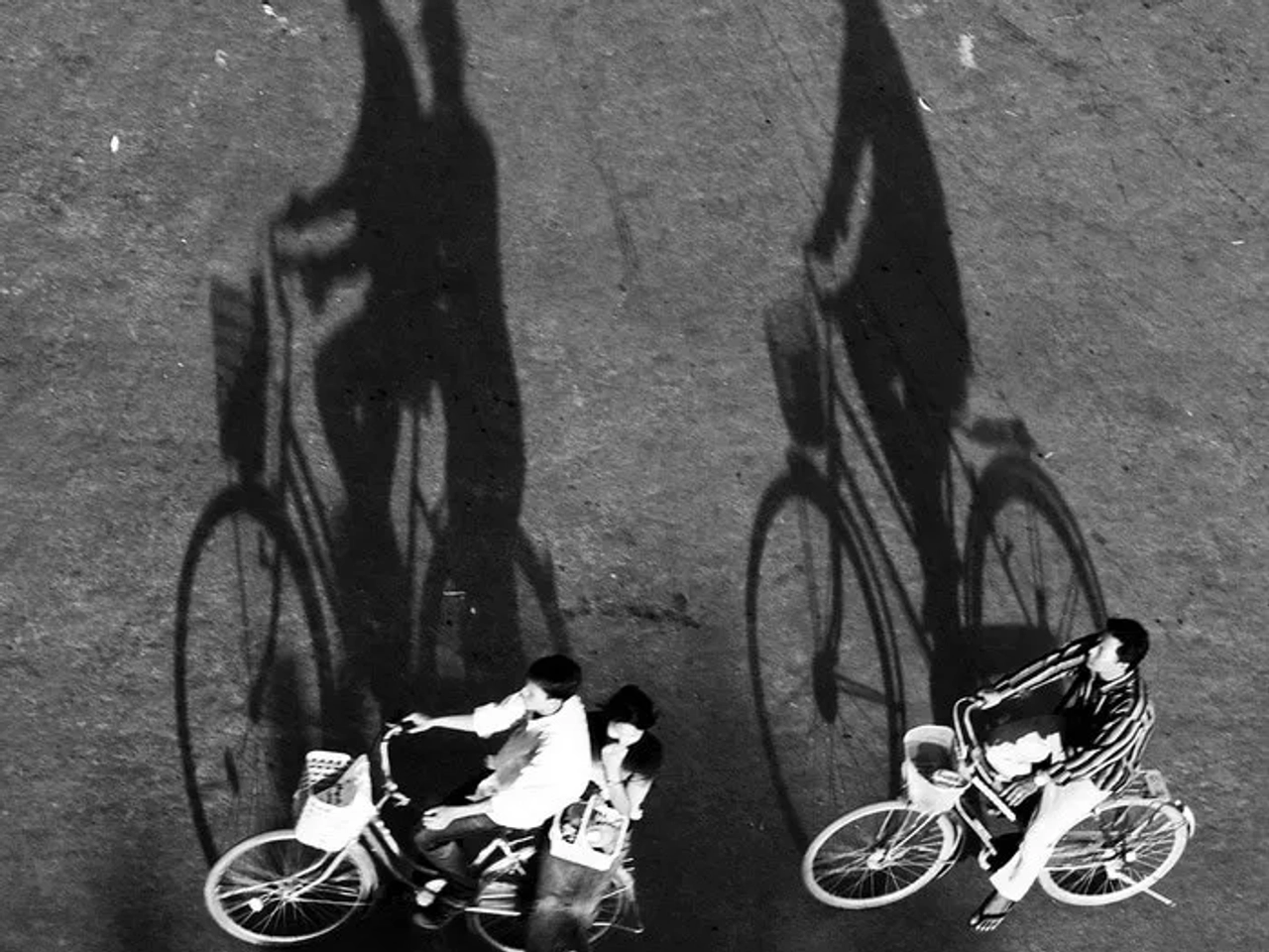 Dos personas montando bicicletas, proyectando sombras alargadas sobre el suelo.