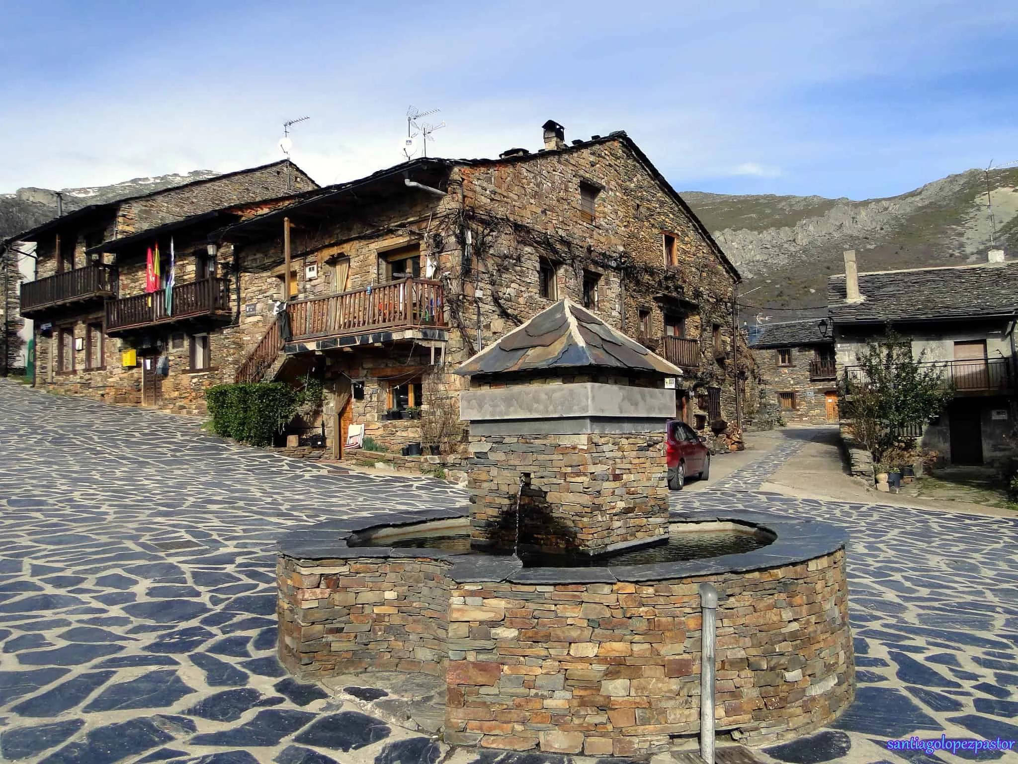 Pitoresca vila espanhola com casas de pedra e fonte central.