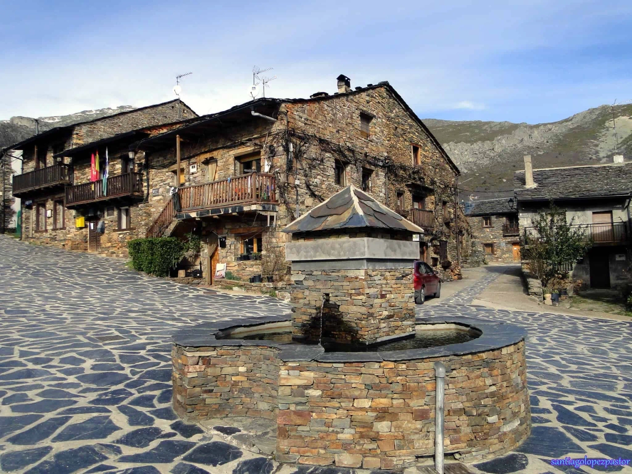 Pitoresca vila espanhola com casas de pedra e fonte central.