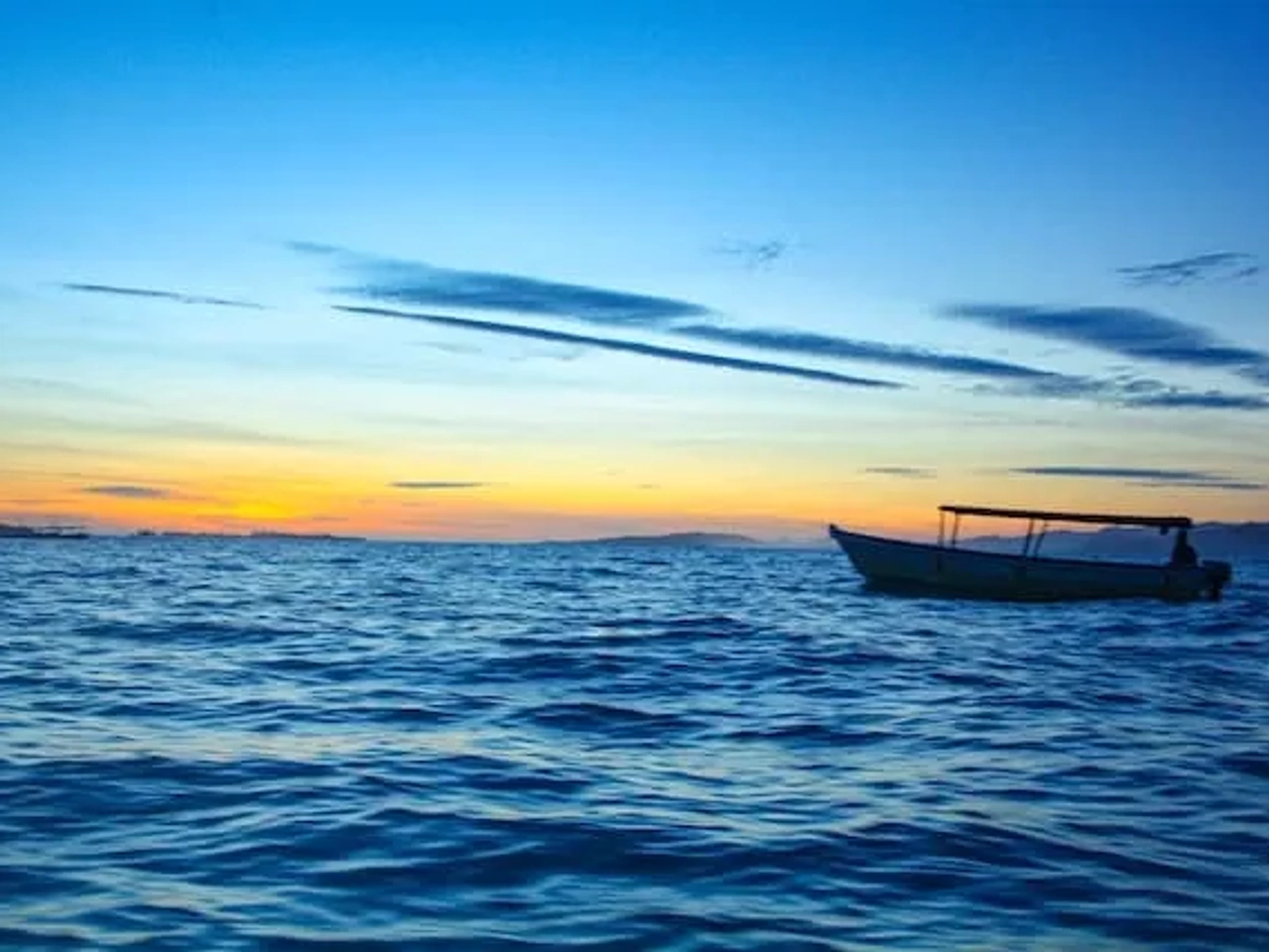 barco no mar com pôr do sol na praia de padang padang