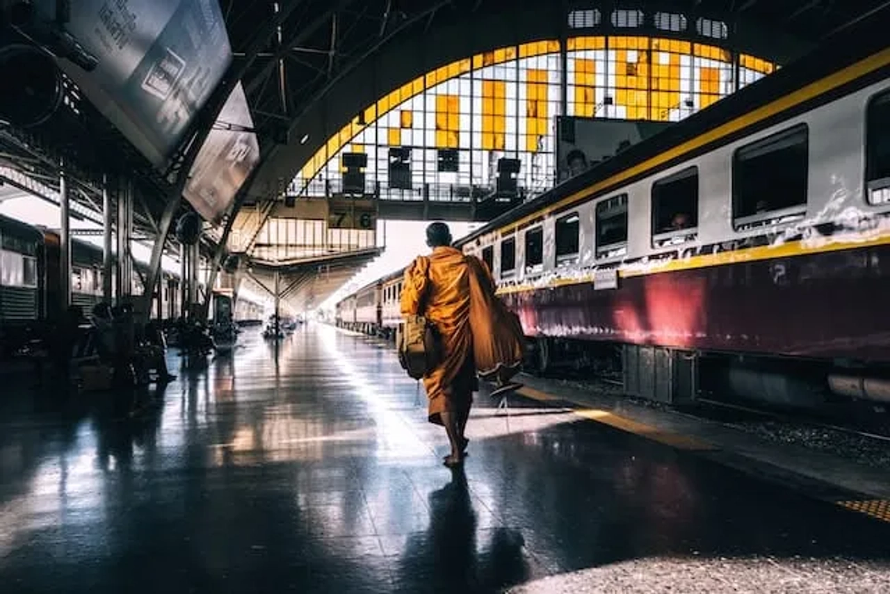 homem vestido de amarelo a caminhar para um comboio na tailandia