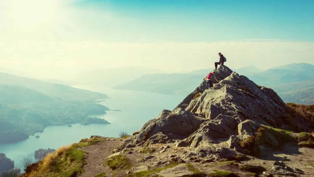 pessoa sentada no topo de uma montanha a contemplar o horizonte