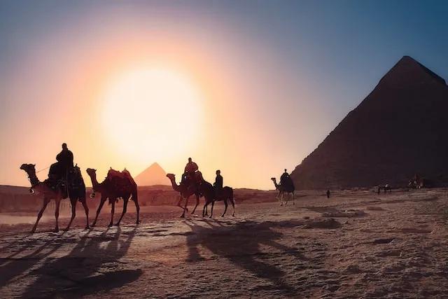 people riding camels in front of a pyramide in egypt