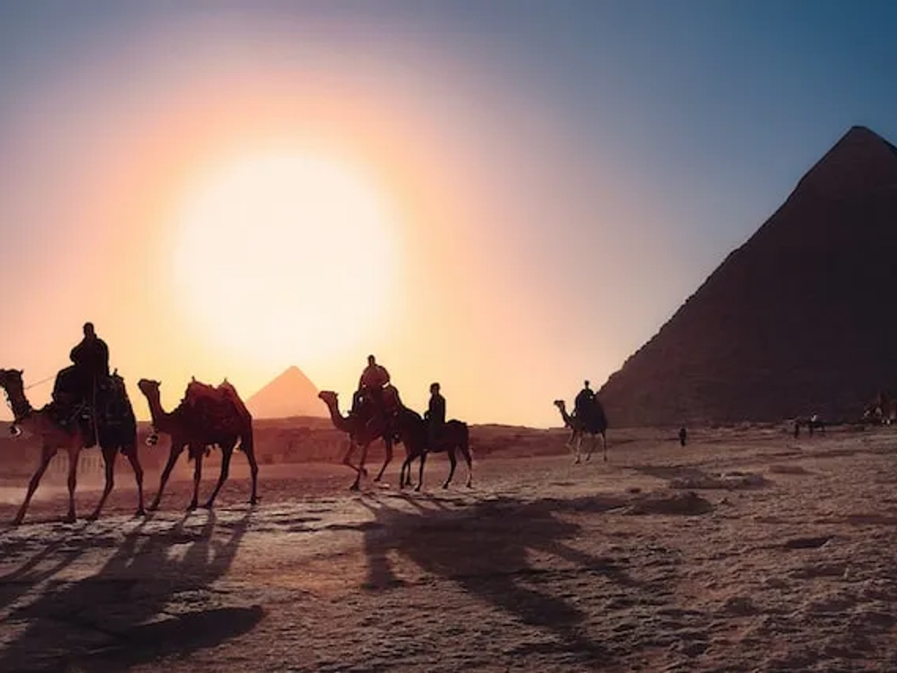 people riding camels in front of a pyramide in egypt