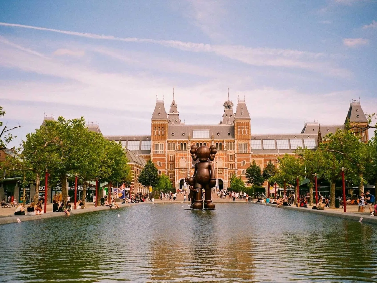 Museo Rijksmuseum con una escultura en el estanque y visitantes disfrutando del paisaje.