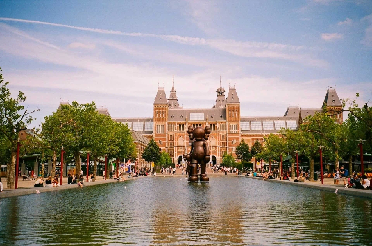 Museo Rijksmuseum con una escultura en el estanque y visitantes disfrutando del paisaje.